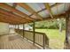 A covered back porch with wooden railing and lattice, overlooking a spacious green yard at 216 Hillcrest Pl, Salisbury, NC 28144