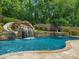 Backyard pool featuring a rock waterfall and slide, surrounded by lush greenery and a wooden fence at 315 Mountainview Dr, Charlotte, NC 28270