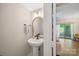 A powder room with a pedestal sink, rounded mirror, and views of the backyard at 3737 Winding Creek Ln, Charlotte, NC 28226