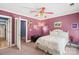 Plum painted bedroom featuring a white bed, an open door, and a ceiling fan at 4740 Myers Ln, Harrisburg, NC 28075
