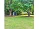 Private backyard featuring mature trees, a lush lawn, and a storage shed at 4906 Charleston Dr, Charlotte, NC 28212
