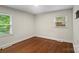 A bright bedroom has hardwood floors with two windows overlooking lush greenery for natural light at 4906 Charleston Dr, Charlotte, NC 28212