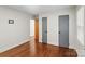 A bedroom with hardwood floors features two gray-toned closet doors and an entranceway to the main room at 4906 Charleston Dr, Charlotte, NC 28212
