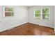 A bedroom boasts hardwood floors and dual windows with tree-lined views and natural light throughout at 4906 Charleston Dr, Charlotte, NC 28212