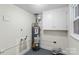 Utility room features a water heater with updated plumbing and white storage cabinets above an epoxy painted floor at 4906 Charleston Dr, Charlotte, NC 28212
