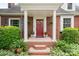 Welcoming red front door with a wreath, flanked by potted plants and manicured bushes at 81 21St Nw Ave, Hickory, NC 28601