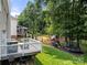 Large, green backyard with play equipment, a deck, mature trees, and a wood fence surrounding the property at 8500 Headford Rd, Charlotte, NC 28277