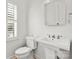 Elegant bathroom with pedestal sink, toilet, and shuttered window at 8500 Headford Rd, Charlotte, NC 28277