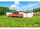 Exterior of a white home with a metal roof, wooden deck and shed in a lush, green backyard at 1016 S D Ave, Maiden, NC 28650