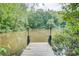 Private wooden dock featuring solar lights surrounded by lush greenery overlooking the calm lake at 1062 Willow Ridge Ln, Fort Mill, SC 29707