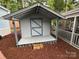 Gray wooden shed with a small porch and blue trim at 107 Pine St, New London, NC 28127