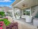 Covered patio with white furniture, ceiling fan, adjacent planting, and light gray siding at 1226 Restoration Dr, Waxhaw, NC 28173