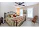 Cozy bedroom with a decorative wrought iron bed, ceiling fan, and natural light from two windows at 2031 Brook View Ct, Matthews, NC 28104