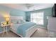 Comfortable bedroom features a white bed frame, soft blue accents, and plenty of natural light from the large window at 2031 Brook View Ct, Matthews, NC 28104