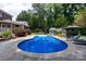 Backyard featuring a sparkling pool with an ornate tile design surrounded by a large patio and lush landscaping at 2031 Brook View Ct, Matthews, NC 28104