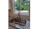 Close-up of a stainless steel kitchen sink with granite countertops, complemented by a window view of the backyard at 242 North Ave, Troutman, NC 28166