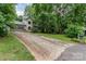 View of exterior showing a long driveway leading to a charming home surrounded by lush greenery and mature trees at 3884 Snider Cir, Hickory, NC 28602