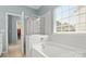 Bright bathroom showcasing a tub with a glass shower door enclosure under a sunlit window at 424 Paperbark Ln, Rock Hill, SC 29732