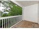 Covered outdoor balcony features wood flooring and white railing with a peaceful view of the lush landscape at 5601 Fairview Rd # 11, Charlotte, NC 28209