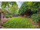 Well maintained backyard with a green lawn, wooden fence, mature trees and manicured landscaping at 7101 Weavers Run, Cramerton, NC 28032