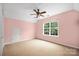 Bedroom showcasing a window and carpeted floors, painted in a serene pink at 7101 Weavers Run, Cramerton, NC 28032