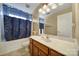 Bathroom with a vanity with wood cabinets, a single sink, a large mirror, and a shower with blue curtain at 920 Old Forester Ln, Charlotte, NC 28214