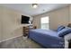 A bright, carpeted bedroom features a built-in media cabinet, a queen bed, and a large window at 920 Old Forester Ln, Charlotte, NC 28214