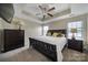 Bedroom with a bed, tray ceiling with a ceiling fan, a dresser with lamp, and windows for natural light at 920 Old Forester Ln, Charlotte, NC 28214