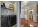 Bright laundry room featuring modern washer and dryer units with overhead shelving for convenient storage at 920 Old Forester Ln, Charlotte, NC 28214