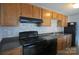 Kitchen featuring wood cabinets, black appliances, and tile backsplash at 9501-A Shannon Green Dr, Charlotte, NC 28213
