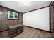 Cozy bedroom featuring a wood-trimmed window, wood-paneled wall, and light wood flooring at 985 Needmore Rd, Woodleaf, NC 27054