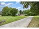 Long concrete driveway leads to a single-story home with manicured lawn, mature trees, and inviting curb appeal at 985 Needmore Rd, Woodleaf, NC 27054