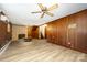 Spacious living room featuring wood paneling, brick fireplace, ceiling fan and wood-look flooring at 985 Needmore Rd, Woodleaf, NC 27054