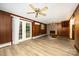 Living room with wood paneling and wood-look floors, complemented by a brick fireplace and glass patio doors at 985 Needmore Rd, Woodleaf, NC 27054