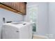 Bright laundry room featuring a modern washer and dryer, cabinets, and a large window for natural light at 1011 Bydeford Ct, Matthews, NC 28105