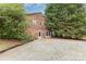 The home's back exterior features brick, a door, and gravel with mature landscaping at 115 Turner St, Lincolnton, NC 28092