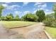 Long gravel driveway with a brick home, mature trees and lush green grass at 115 Turner St, Lincolnton, NC 28092