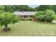 Aerial view of a charming brick ranch home featuring a well-manicured lawn and mature trees at 115 Turner St, Lincolnton, NC 28092