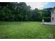 Large grassy backyard bordered by lush trees, offering a private outdoor retreat at 11841 Churchfield Ln, Charlotte, NC 28277