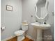 A clean half bathroom with a pedestal sink, decorative mirror, and framed wall art at 124 Vintage Woods Ct, Shelby, NC 28150