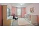 A bright Bedroom features pink walls, a white crib with storage, rocking chair, and white dresser at 124 Vintage Woods Ct, Shelby, NC 28150