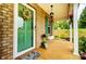 Close-up of a charming front porch with a decorated green door, brick wall, and a hanging lantern at 124 Vintage Woods Ct, Shelby, NC 28150