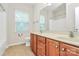 Well-lit bathroom with double vanity, wood cabinets, tile floors, and a large window for natural light at 14904 Rosemary Way Dr, Huntersville, NC 28078
