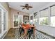 Sunroom featuring a wooden table, black metal chairs, ceiling fan and access to the living room and backyard at 14904 Rosemary Way Dr, Huntersville, NC 28078