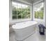 Spa-like bathroom featuring a freestanding tub with a view of the surrounding greenery through large windows at 19625 Callaway Hills Ln, Davidson, NC 28036