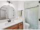 Well-lit bathroom with a white quartz countertop, wood cabinets, modern fixtures, and a shower behind a curtain at 2018 Whiskery Ct, York, SC 29745