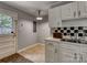A kitchen area features a sink set in white cabinetry with a black and white tiled backsplash and access to an exterior door at 24 19Th Nw St, Hickory, NC 28601