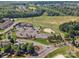 Aerial view of a golf course with surrounding clubhouse, parking area, trees, and lake view at 26444 Sandpiper Ct, Fort Mill, SC 29707