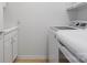 Clean, tiled laundry room features a newer washer, dryer, and built-in cabinets at 26444 Sandpiper Ct, Fort Mill, SC 29707