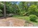 Backyard featuring a brick patio, lush trees, and a swing at 2813 Hilliard Dr, Charlotte, NC 28205